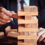 photo of hands playing jenga, a game of managing risk